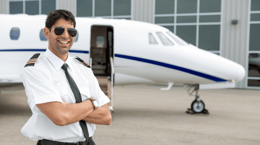 Male pilot standing in front of plane with sunglasses on and arms crossed